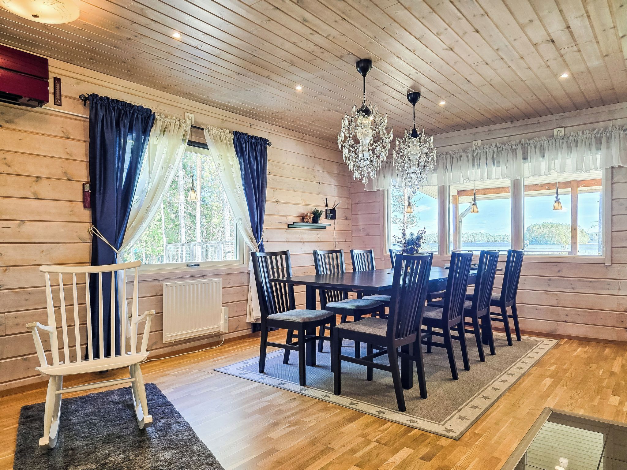 Una habitación con paneles de madera, una mesa de comedor, sillas, un banco blanco y una araña.