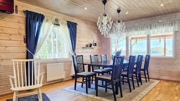Una habitación con paneles de madera, una mesa de comedor, sillas, un banco blanco y una araña.