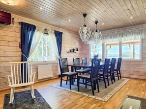 A wooden-paneled room with a dining table, chairs, a white bench, and a chandelier. - Oravajärven talo (ent. suomela) by Interhome (Ranua)