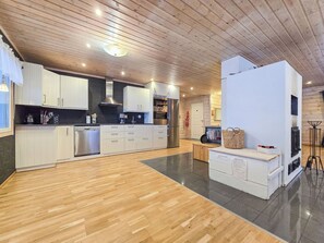 Eine moderne Küche mit Holzboden, weißen Schränken, Edelstahlgeräten und einem großen, weißen Schrank mit einem Schild.
