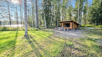 A wooden cabin with a stone foundation, surrounded by a forest and a lake.