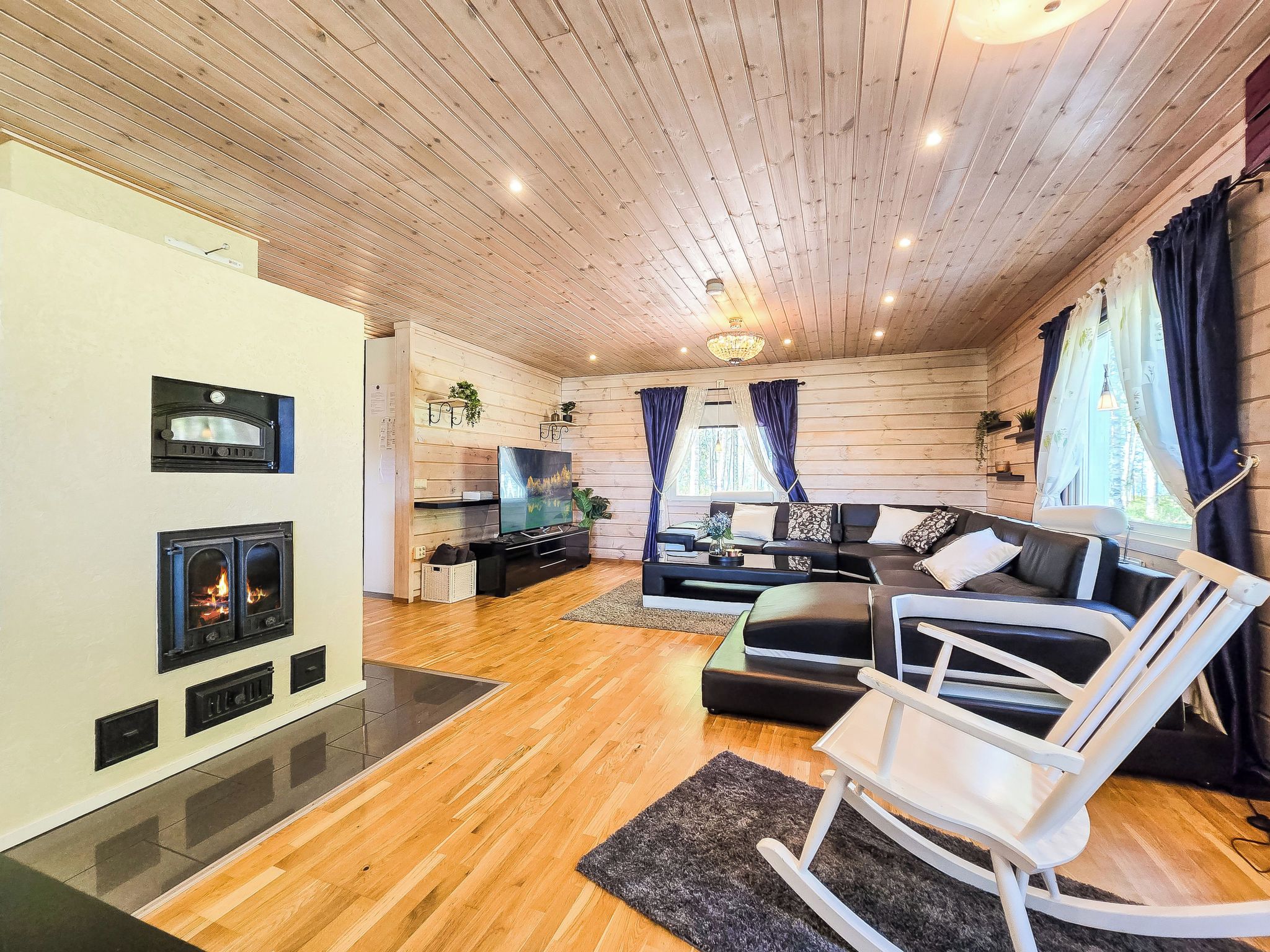 Ein gemütliches Wohnzimmer mit Kamin, Holzboden, einer Sofagarnitur und einem Schaukelstuhl.