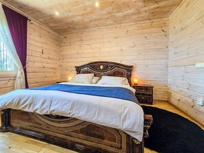 Una habitación con paneles de madera, una cama, una mesita de noche y un ventanal con cortinas.