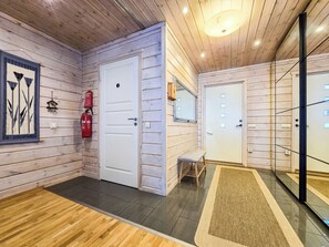 Un pasillo con paredes de madera, un extintor, un banco y una puerta con un espejo.