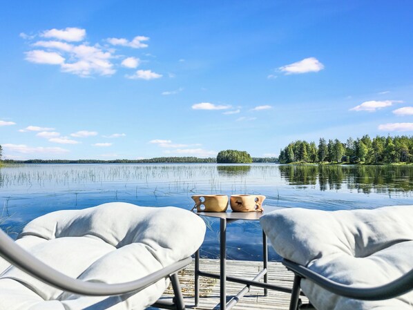 A lakeside view with a wooden dock, two lounge chairs, and a small table with two wooden bowls. - Oravajärven talo (ent. suomela) by Interhome (Ranua)