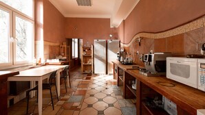 Eine Küche mit Holztisch, Stühlen, einem Kühlschrank, einer Mikrowelle und einer Kaffeemaschine.
