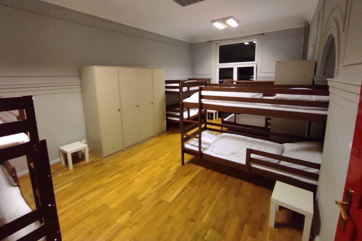 Un dormitorio con literas, una mesita, un armario y una ventana.