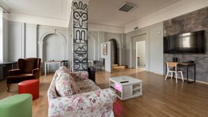 Ein großzügiger Wohnbereich mit Sofa, Hocker und einem großen Fernsehbildschirm.