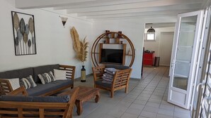 Una sala de estar con un sofá, sillas, una mesa de centro y un mueble para televisión.