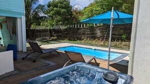 Un patio trasero con un jacuzzi, una piscina y sillas de descanso.