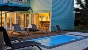 Una piscina con sillones de descanso y un patio cubierto.