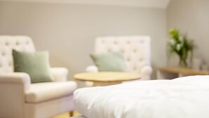 A bedroom with a bed, two armchairs, a small round table, and a plant. - Reetdachhaus in Dranske (Dranske)