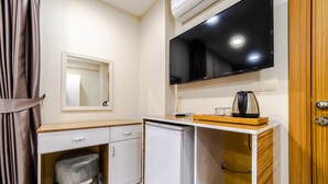 Una kitchenette compacta con microondas, un refrigerador pequeño, un lavamanos y un televisor de pantalla plana montado en la pared.