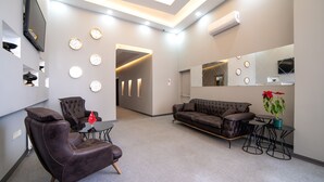 Una sala de estar moderna con un sofá de cuero, un sillón de cuero, una mesita y una planta en maceta.