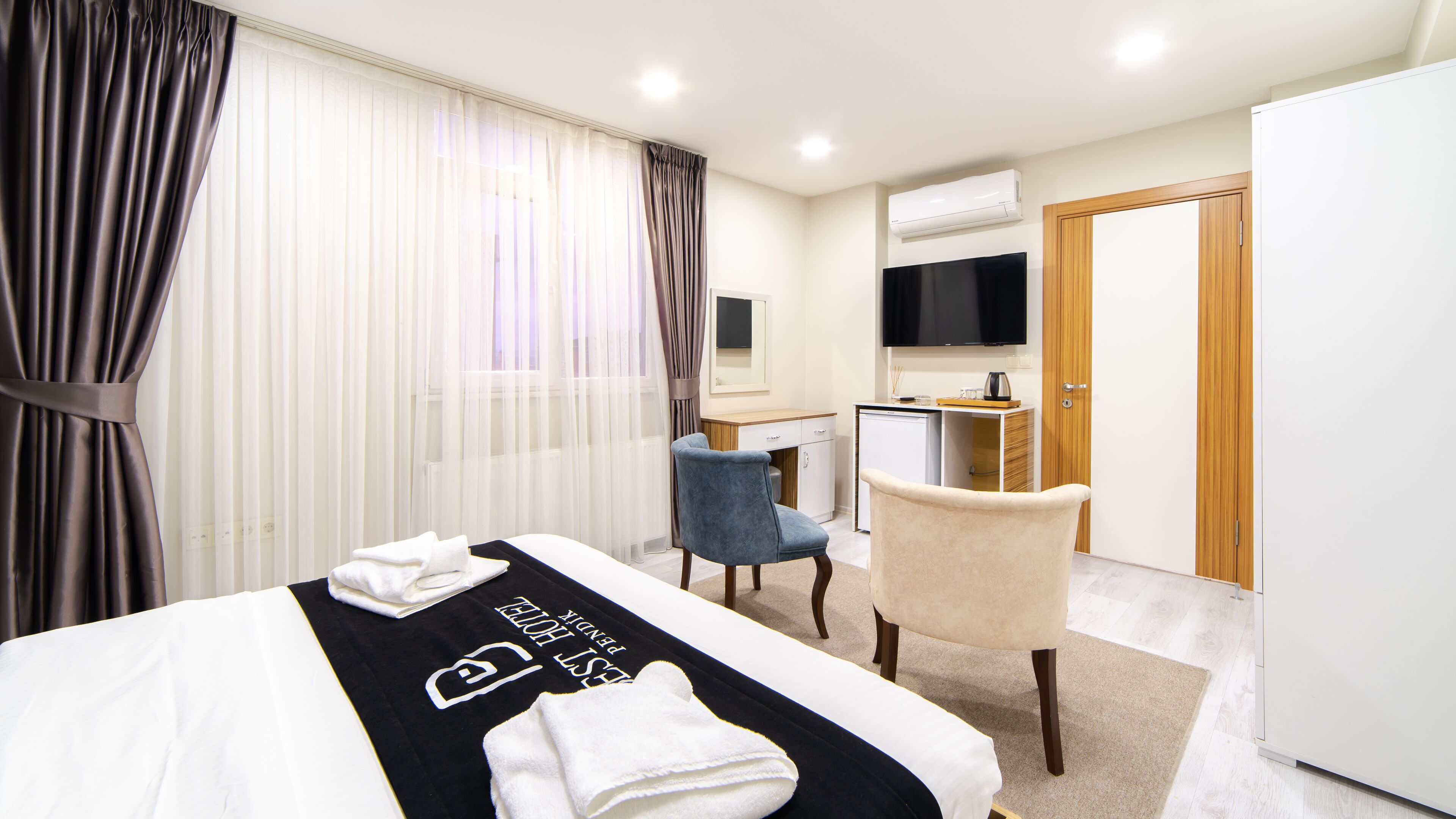 Una habitación de hotel con cama, escritorio, silla, televisión y armario.