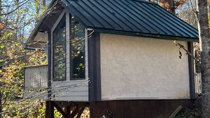 Eine Holzhütte mit einem Metalldach, großen Fenstern und einer Holzdielen-Terrasse.