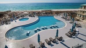 Une piscine à la forme originale, entourée de chaises longues et de parasols, avec vue sur une plage.