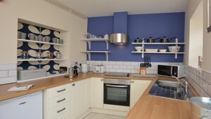 Eine moderne Küche mit weißen Schränken, einer Holz Arbeitsplatte, einem eingebauten Ofen und einer Mikrowelle.