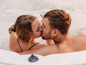 Una pareja en un jacuzzi con una escultura de piedra.