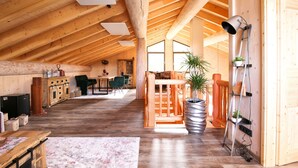 Un loft spacieux avec de hauts plafonds, des poutres en bois et une grande fenêtre laissant entrer la lumière naturelle.