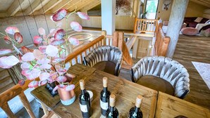 Une table à manger en bois, avec quatre bouteilles de vin et un vase rempli de fleurs roses.
