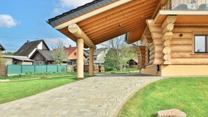 Une cabane en rondins dotée d’un porche couvert, d’un chemin en pierre et d’une cour gazonnée.