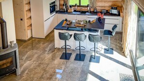 Une cuisine moderne dotée d’un îlot central, de tabourets de bar et d’une grande fenêtre qui laisse entrer la lumière naturelle.
