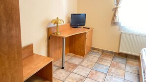 A small, well-lit room with a wooden desk, a laptop, a lamp, and a radiator. - Single room (Pulheim)