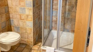 A bathroom with a glass-enclosed shower, a toilet, and tiled walls. - Single room (Pulheim)