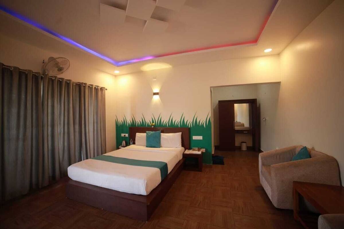 A hotel room with a bed, a chair, a desk, and a mirror.