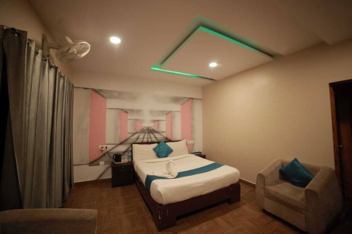 A bedroom with a bed, bedside table, chair, and a ceiling fan.
