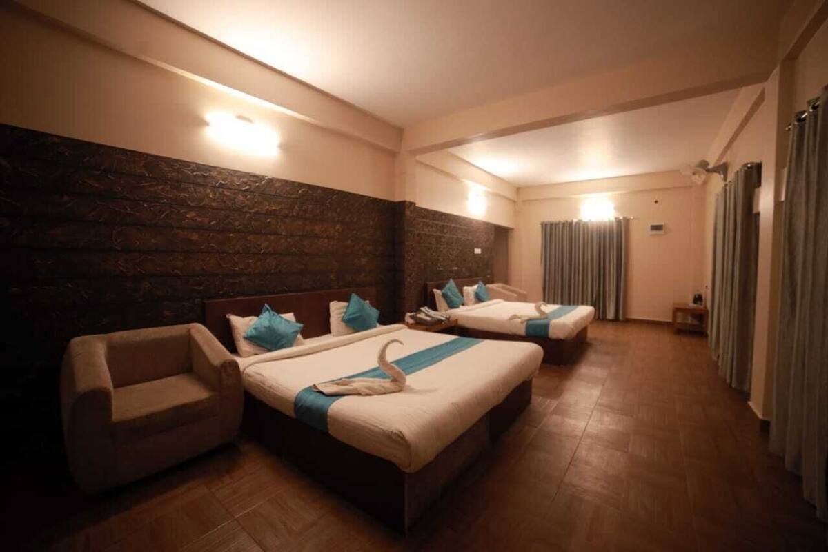 A hotel room with two beds, a sofa, and a stone wall.