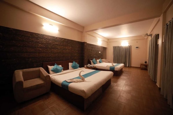 A hotel room with two beds, a sofa, and a stone wall. - Misty Dam Resort (Vythiri)