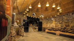 A room with a stone wall, a wooden bench, and a staircase leading to an upper level.