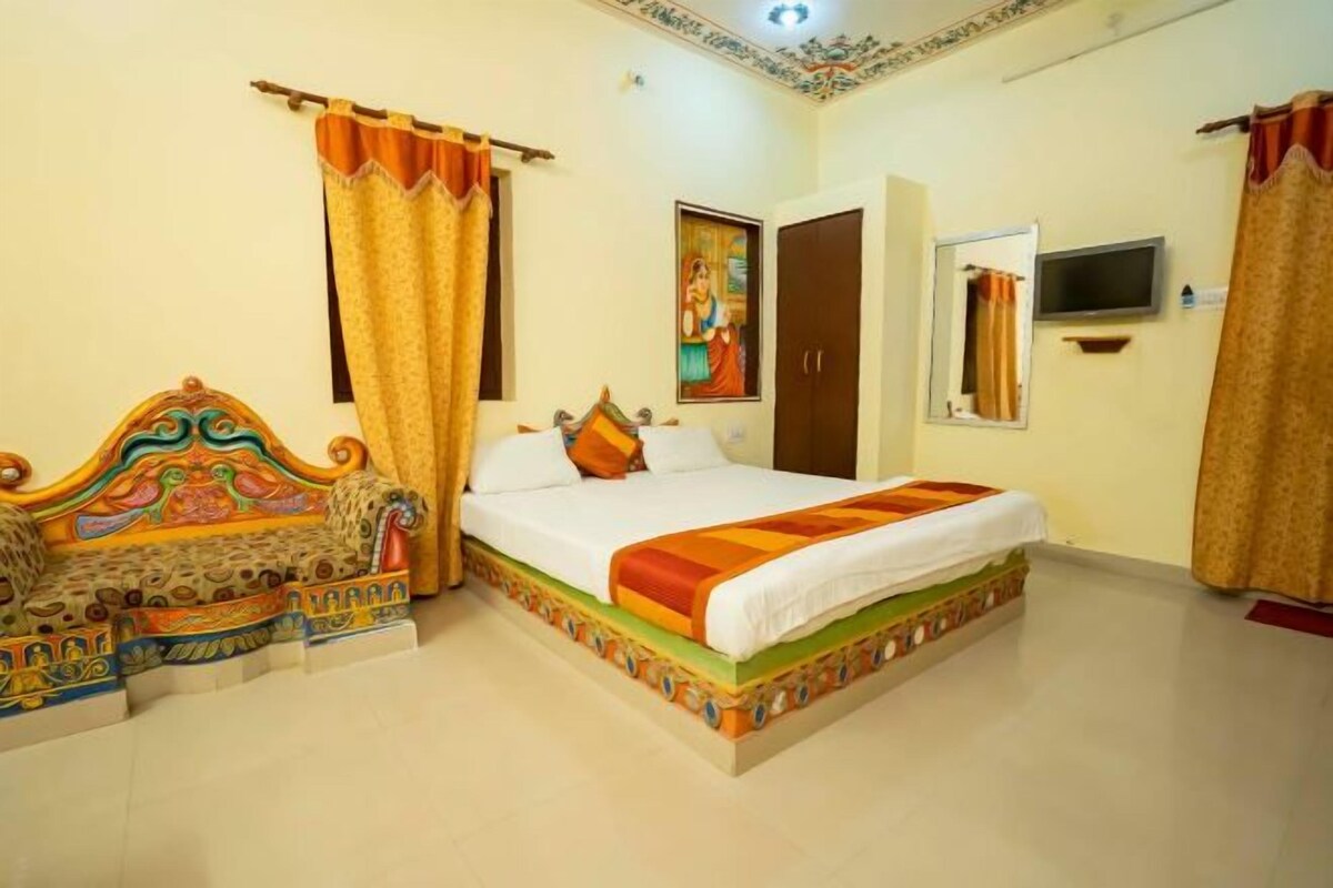 A hotel room with a bed, a sofa, a television, and a door.