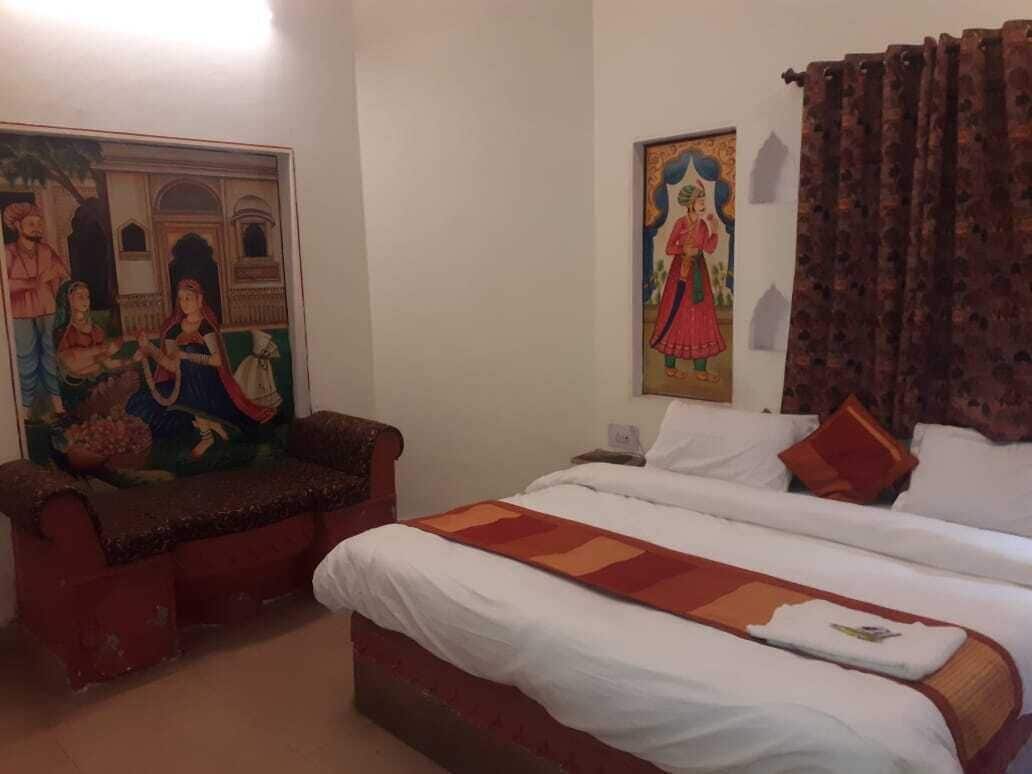 Une chambre d’hôtel avec un lit, un canapé et deux tableaux accrochés au mur.
