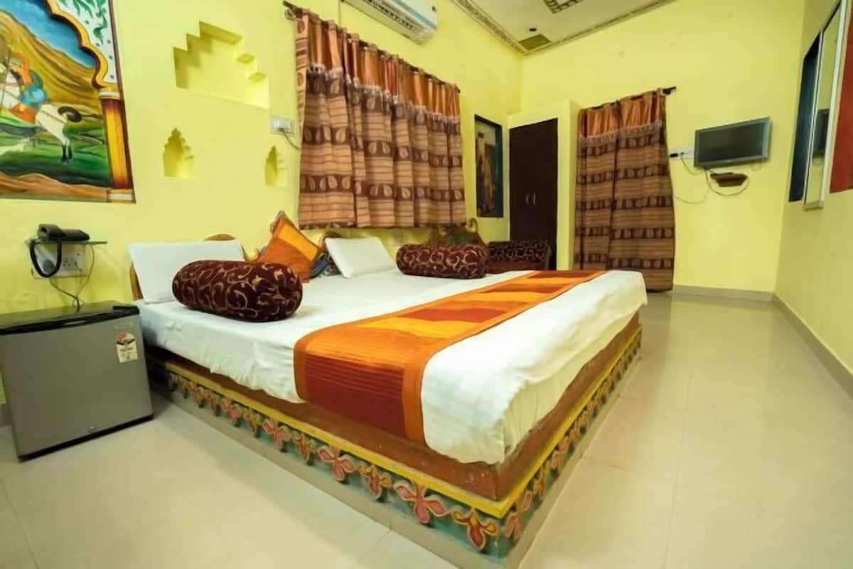 A bedroom with a bed, curtains, a television, and a refrigerator.