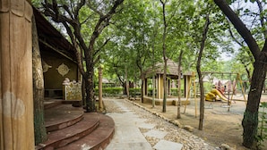 A park with a stone pathway, a gazebo, and a playground with swings and slides.