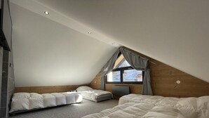 Un dormitorio con dos camas, una ventana con cortinas y un techo inclinado.