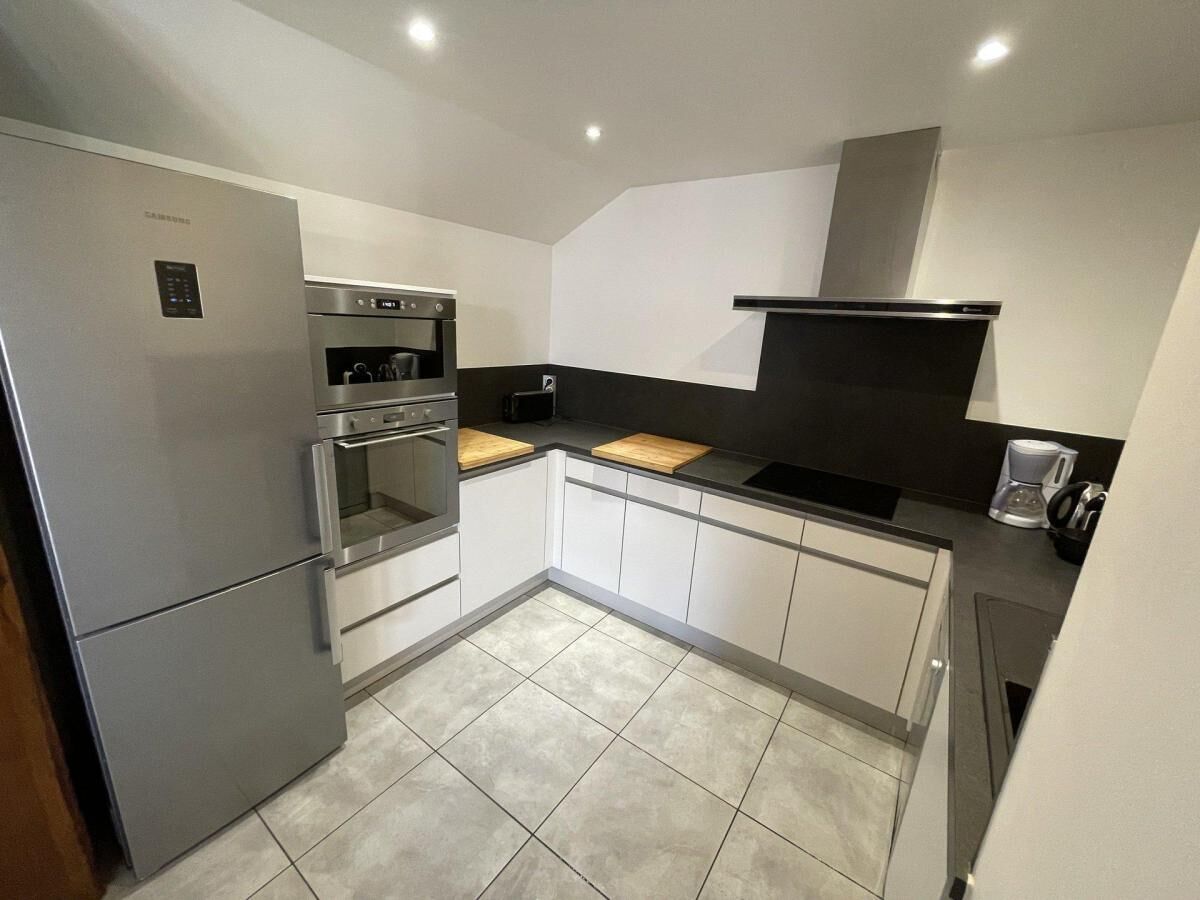 A compact kitchen with a built-in oven, a refrigerator, and a microwave.