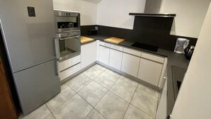 Una cocina compacta con horno empotrado, refrigerador y microondas.