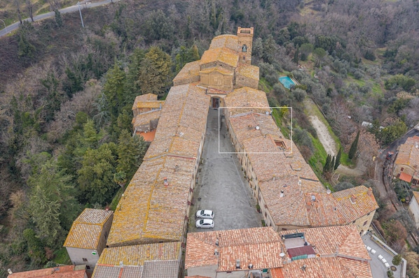 An aerial view of a building with a central courtyard, surrounded by terraced roofs and a tower.