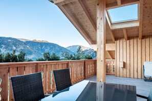 A wooden deck with a glass table and chairs, overlooking a mountainous landscape. - Holiday Apartment Mittnackerhof Melisse with Mountain View, Balcony & Wi-Fi (Sarentino)