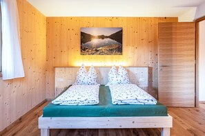 Una habitación con paneles de madera, una cama, un cuadro en la pared y una puerta.