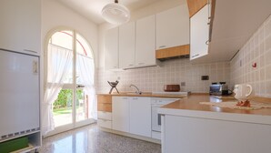 A modern kitchen with white cabinets, a granite countertop, and a large window. - Villa "Delle Pomelie" with Private Garden, Balconies, and Wi-Fi (Furnari)