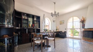 A spacious kitchen with granite countertops, a dining area with chairs, a chandelier, and large windows with curtains. - Villa "Delle Pomelie" with Private Garden, Balconies, and Wi-Fi (Furnari)