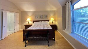 Quarto com uma cama grande, duas luminárias de cabeceira, um ventilador de teto e uma janela com persianas.
