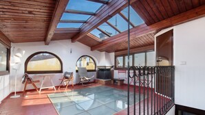 A spacious room with a glass floor, wooden ceiling beams, and large windows.