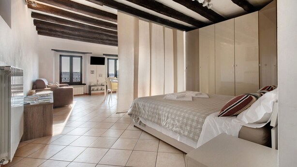 A bedroom with a large bed, a desk, and a view of the outside.