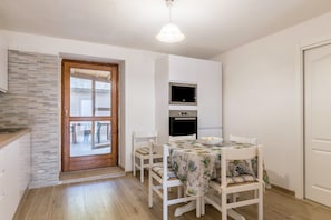 Una cocina compacta con microondas, horno y comedor con mesa y sillas.